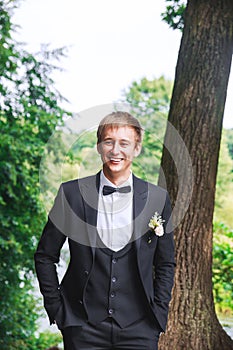 Groom at wedding tuxedo smiling and waiting for bride. Rich groom at wedding day. Elegant groom in costume and bow-tie.