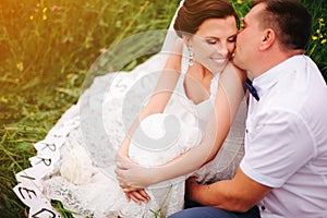 Groom whispering on the ear of his bride, she smiling