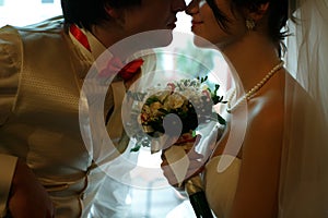 Groom in a white waistcoat leans to a pretty bride