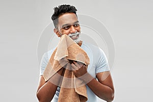 Man removing shaving foam from face by towel