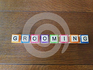 Grooming word in colorful letters on wood background