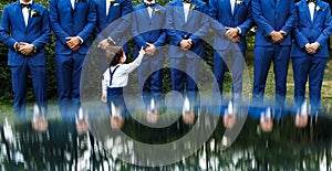 The groomsman in blue suits stand in a row