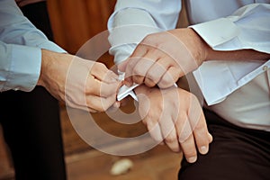 Groomsman helping the groom with his cuff buttons