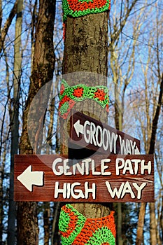 Groovy way sign and gentle way on crochet trees in woods on a trail.