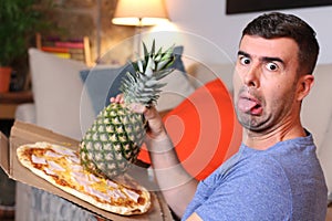 Grossed out man holding pineapple and pizza photo