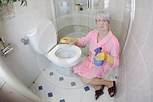 Grossed out senior woman cleaning the toilet