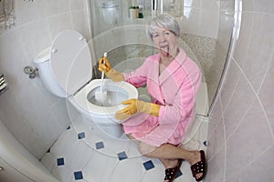 Grossed out senior woman cleaning the toilet photo