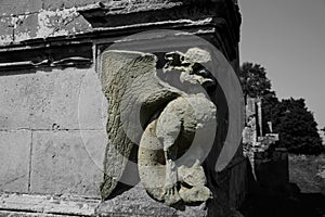 Grotesque gargoyle carving in stone on an old house photo