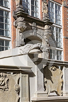 Grotesque gargoyle on front of colorful tenement house, Gdansk, Poland