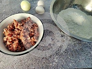 Ground beef, eggs, onions and wheat flour.  Ingredients for making dumplings
