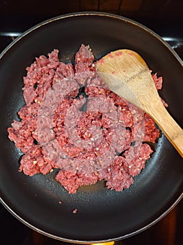 Ground beef in a frying pan with wooden spoon