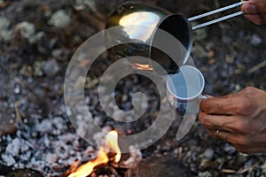 Ground black coffee in a copper Turk is brewed and boils on camp fire.