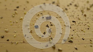 Ground black pepper drops on a wooden surface. Macro shot of black pepper. Slow motion.