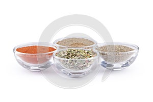 Ground black pepper, paprika, coriander and italian herbs in glass bowls isolated on white background