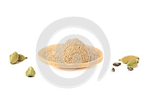 Ground cardamom on a wooden bowl and pods with cardamom seeds on a white background.