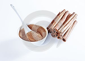 Ground cinnamon in a ceramic bowl, ceramic spoon, cinnamon whole