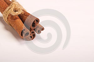 Ground cinnamon, cinnamon sticks, tied with jute hempen rope on wooden white background, selective soft focus