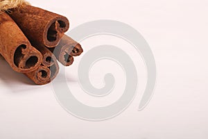 Ground cinnamon, cinnamon sticks, tied with jute hempen rope on wooden white background, selective soft focus