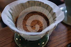 Ground coffee in a coffee dripper green ceramic cone at coffee d