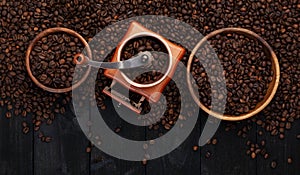 Ground coffee, coffee mill, bowl of roasted coffee beans on black wooden background, top view