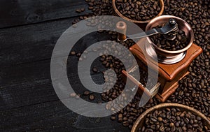 Ground coffee, coffee mill, bowl of roasted coffee beans on black wooden background, top view