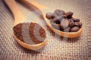 Ground coffee and grains with wooden spoon on jute canvas