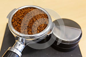 Ground coffee in portafilter and coffee leveler