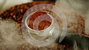 Ground coffee in portafilter on wooden board with coffee beans and dissipating steam. Freshly ground coffee in filter