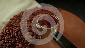 Ground coffee in portafilter on wooden board with coffee beans and dissipating steam. Freshly ground coffee in filter