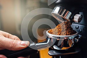 Ground coffee pouring into a portafilter with a grinder