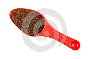 Ground coffee in red plastic spoon isolated on white
