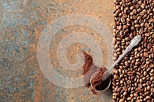 Ground coffee in a spoon and coffee beans on a rusty metal background