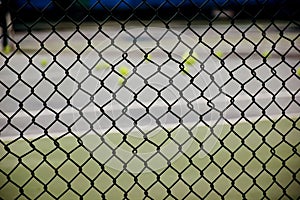 Ground court with net and many yellow tennis balls
