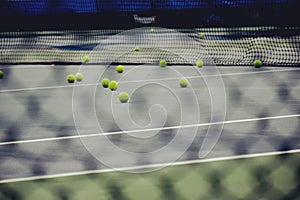 Ground court with net and many yellow tennis balls