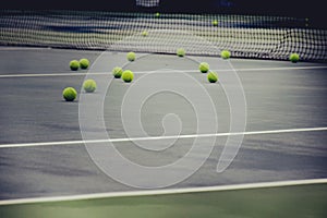 Ground court with net and many yellow tennis balls