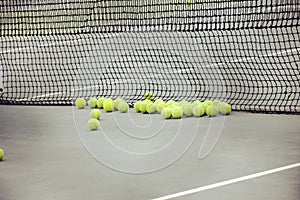 Ground court with net and many yellow tennis balls