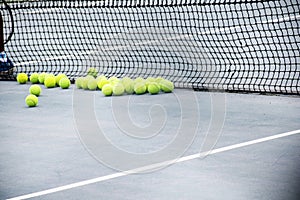 Ground court with net and many yellow tennis balls