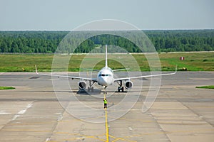 Ground crew in the signal vest. Supervisor meets passenger airplane at the airport. Aircraft is taxiing to the parking place