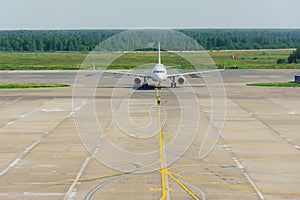 Ground crew in the signal vest. Supervisor meets passenger airplane at the airport. Aircraft is taxiing to the parking place