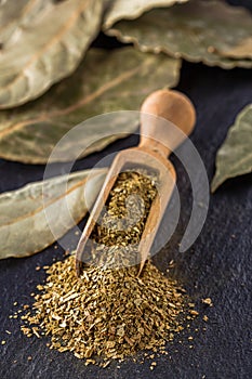 Ground dried bay leaf on a dark stone background