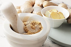 Ground ginger in a mortar, fresh ginger in the background, ginger pieces in a bowl. Spice for recipes. Health and immunity for the