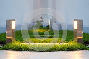 Ground lantern lighting marble walkway in the evening backyard.