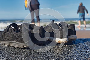 Ground level view of two pairs of shoes on a rock at the beach