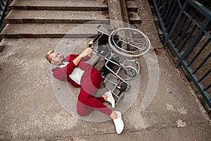 On the ground near the stairs lies a disabled man near the wheelchair. The concept of a wheelchair, disabled person, full life,