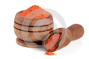 Ground paprika in a wooden bowl with a scoop isolated on a white background