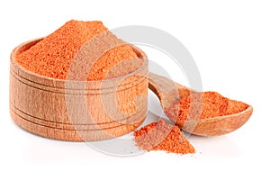Ground paprika in a wooden bowl with a spoon isolated on a white background