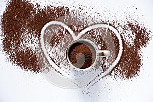 Ground roasted coffee sprinkled on white background and white coffee cup close up close up