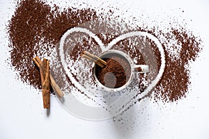 Ground roasted coffee sprinkled on white background and white coffee cup close up close up