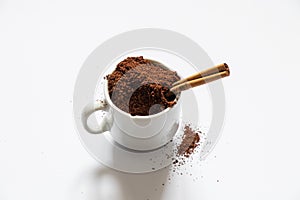 Ground roasted coffee sprinkled on white background and white coffee cup close up close up