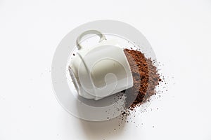 Ground roasted coffee sprinkled on white background and white coffee cup close up close up